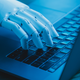 A robot hand uses a laptop keyboard.